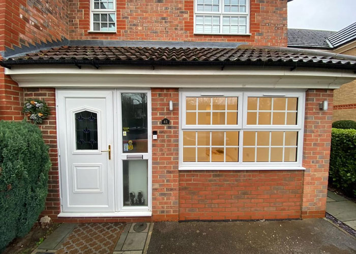 A converted garage at the front of a house, with two large windows.